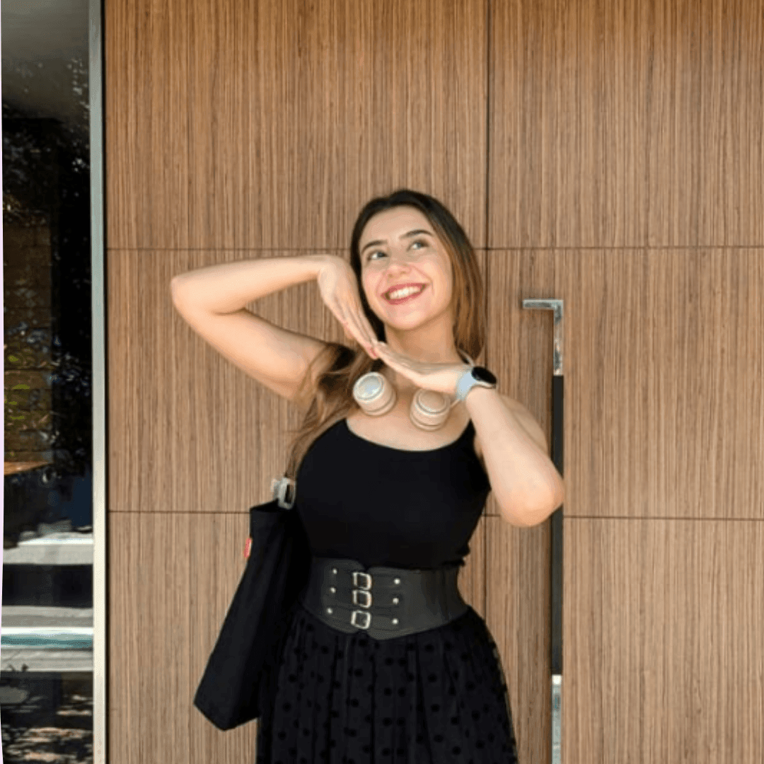 Woman in black dress with headphones smiles, posing in front of a wooden wall.